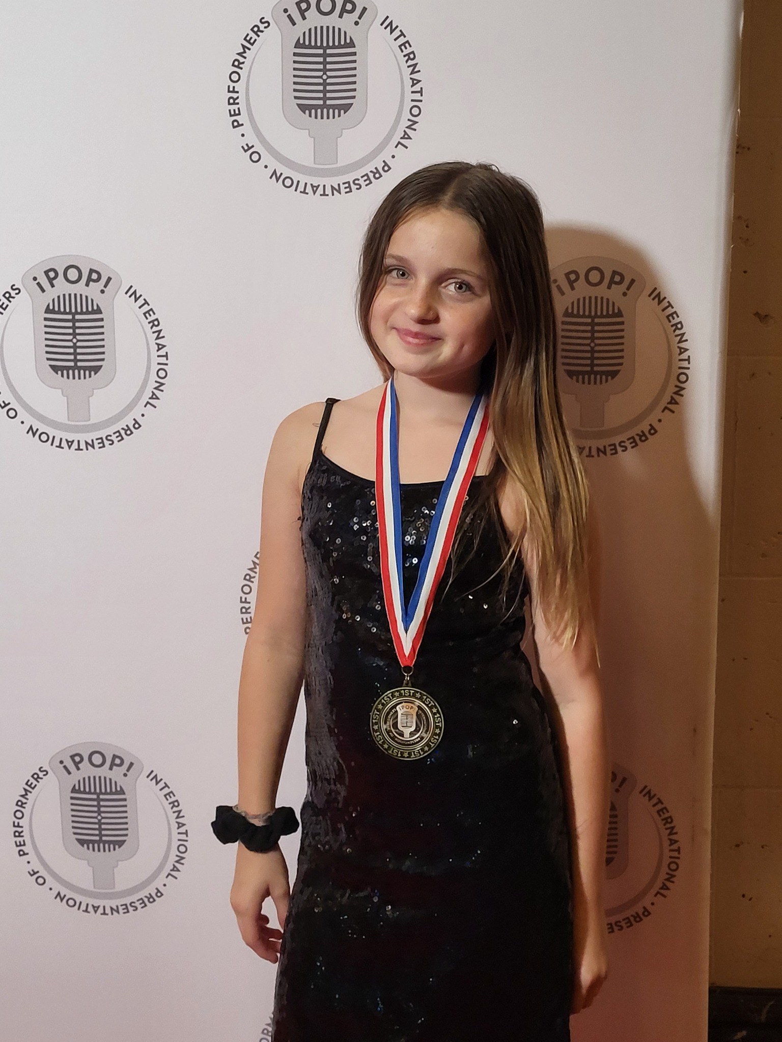 Caitlyn Helms wearing her first-place iPOP medal